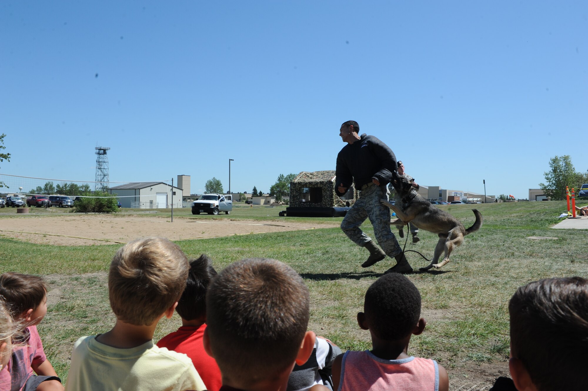 Staff Sgt. Matthew Baxter, 5th Security Forces Squadron K-9 handler, tries to escape military working dog Topi during the “Hero in Training” event at Minot Air Force Base, N.D., July 31, 2015. Baxter demonstrated procedures for apprehending a suspect with the help of MWD Topi and 5th SFS K-9 Handler Senior Airman Andrew McCloy. (U.S. Air Force photo/Senior Airman Stephanie Morris)