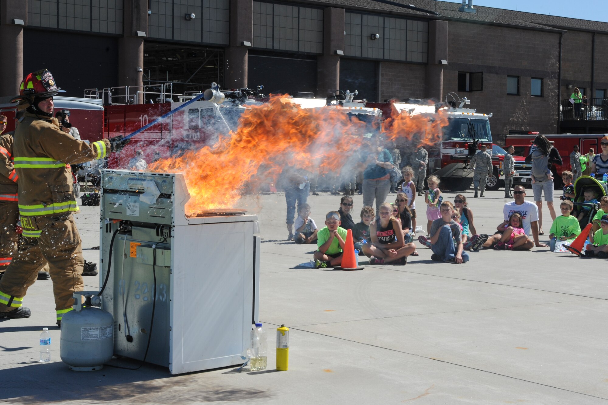 Staff Sgt. Sean Cantrell, 5th Civil Engineer Squadron fire station captain, demonstrates the effects of putting water on a grease fire during the “Hero in Training” event at Minot Air Force Base, N.D., July 31, 2015. The fire department hosted the day-long event which featured displays from their group, the 5th Security Forces Squadron, 5th Medical group and a variety of other base agencies. (U.S. Air Force photo/Senior Airman Stephanie Morris)