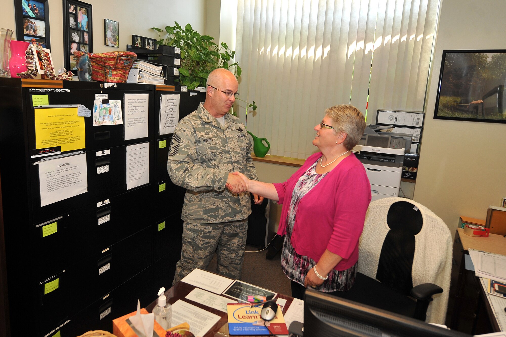 U.S. Air Force Chief Master Sgt. Michael Morris, 55th Wing command chief, coins Pamela Clark, 55th Wing Judge Advocate tax representative, July 31 at the tax center housed out of Offutt Air Force Base, Nebraska, legal office. Clark and her volunteers grossed more than $5 million in refunds last year. (U.S. Air Force photo by Josh Plueger)
