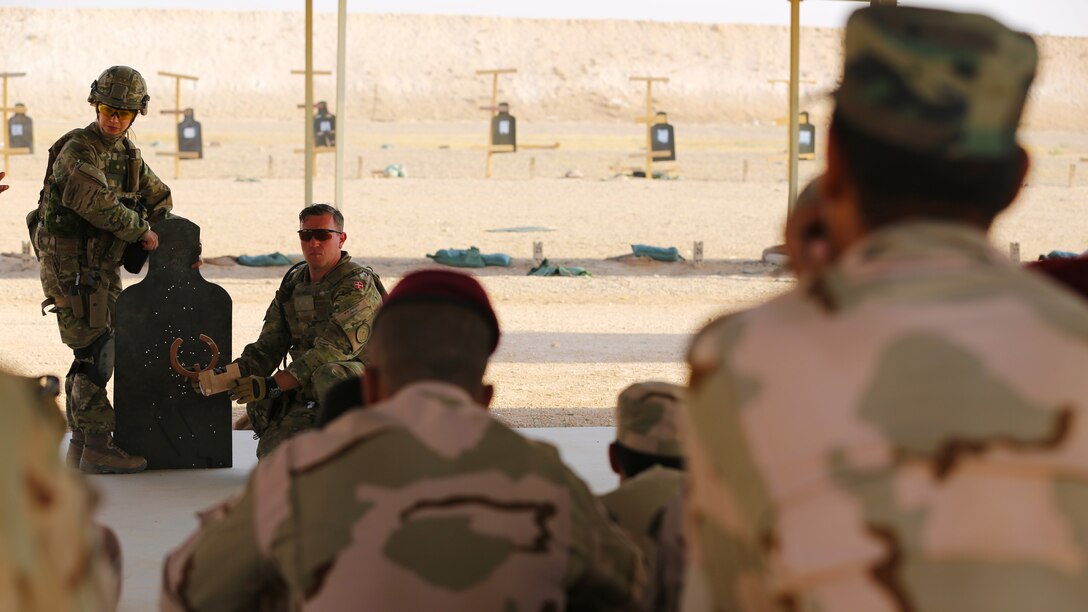 A Danish coalition member with Task Force Al Asad discusses weapon fundamentals with members of the Iraqi army as part of the building partner capacity mission at Al Asad Air Base, Iraq, July 27, 2015. Through the advise and assist and building partner capacity missions, Combined Joint Task Force — Operation Inherent Resolve’s multinational coalition has trained approximately 11,000 Iraqi security force personnel to defeat the Islamic State of Iraq and the Levant and restore the sovereignty and security of Iraq.