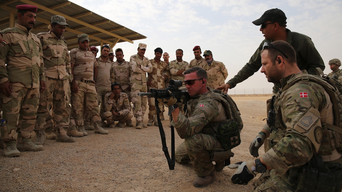 Danish coalition members with Task Force Al Asad explain proper firing positions with Iraqi army soldiers during marksmanship training as part of the building partner capacity mission at Al Asad Air Base, Iraq, July 27, 2015. Through the advise and assist and building partner capacity missions, Combined Joint Task Force — Operation Inherent Resolve’s multinational coalition has trained approximately 11,000 Iraqi security force personnel to defeat the Islamic State of Iraq and the Levant and restore the sovereignty and security of Iraq.