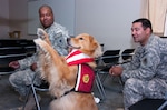 Army Staff Sgt. Anthony Houston, and Staff Sgt. Travis Gilbert, both from the Michigan Army National Guard's 1225th Corps Support Battalion, watch 3-year-old therapy dog, Lugnut, do a trick Aug. 4, 2011, at Camp Atterbury, Ind. The two Soldiers recently returned with their unit from a 10-month deployment in Kandahar, Afghanistan.