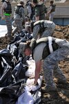 North Dakota National Guard members assist the Corps of Engineers in protecting the Minot, N.D., temporary emergency levees by placing plastic sheeting on them June 26, 2011.