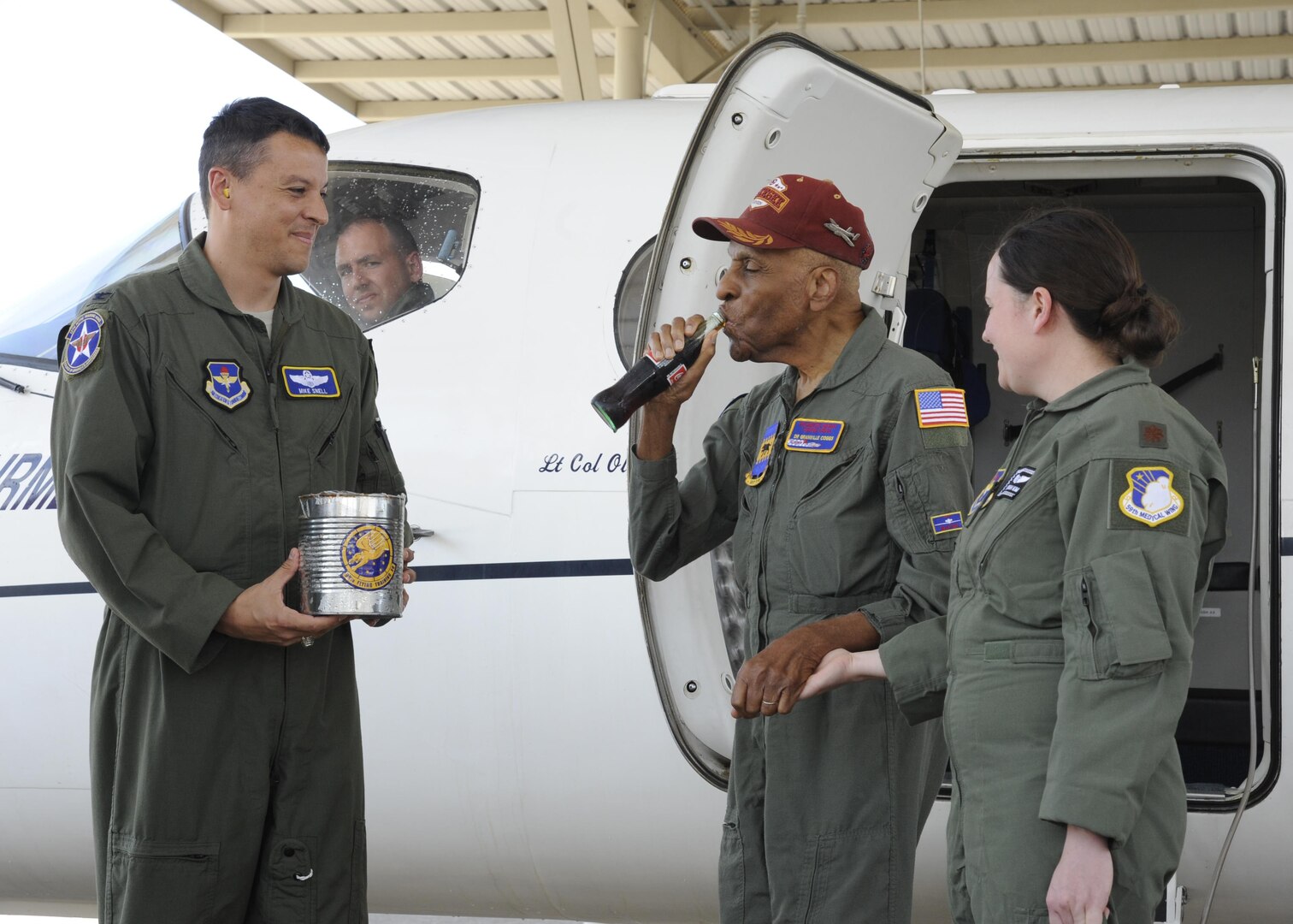 Col. Michael Snell (left), 12th Flying Training Wing vice commander, presents Dr. Granville Coggs (center), documented original Tuskegee Airman, a chilled soda as part of his ‘fini’ flight ceremony for his 90th birthday July 30 at Joint Base San Antonio-Randolph. After his flight with the 99th Flying Training Squadron, Coggs was presented with 99th FTS memorabilia and had his name badge “retired” during a ceremony in his honor.