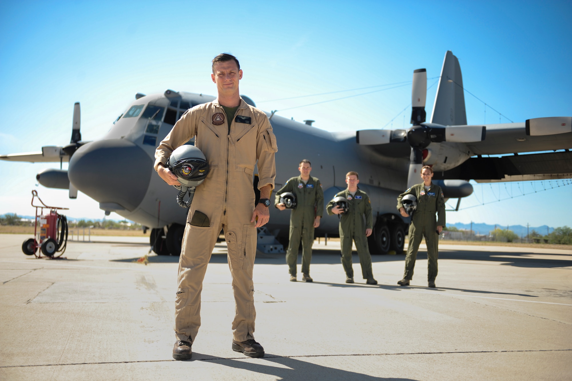 Marine Corps Capt. Jonathon Leach, a 41st Electronic Combat Squadron mission crew commander, stands with Air Force EC-130H Compass Call crewmembers on the flightline at Davis-Monthan Air Force Base, Ariz., July 31, 2015. He is part of a three-year interservice exchange program flying with Airmen from the 41st ECS. Leach is from Marine Corps Air Station Cherry Point, N.C. (U.S. Air Force photo/Airman 1st Class Cheyenne Morigeau)