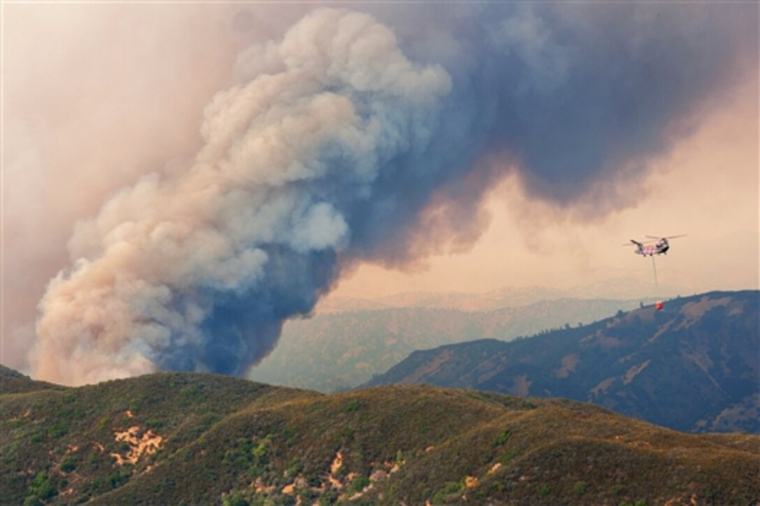 A CH-47D Chinook helicopter prepares to release water from a large bucket onto the Rocky Fire near Clear Lake, Calif., Aug. 1, 2015. 