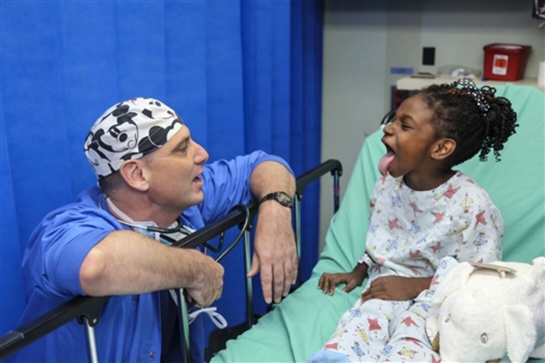 U.S. Navy Cmdr. William Cavill examines a child before her surgery aboard Military Sealift Command hospital ship USNS Comfort during Continuing Promise 2015 in Roseau, Dominica, Aug. 3, 2015. The medical care is part of Continuing Promise, a civil-military effort that includes humanitarian-civil assistance, subject matter expert exchanges, medical, dental, veterinary and engineering support. Cavill is an anesthesiologist assigned to Naval Hospital Pensacola Fla. 