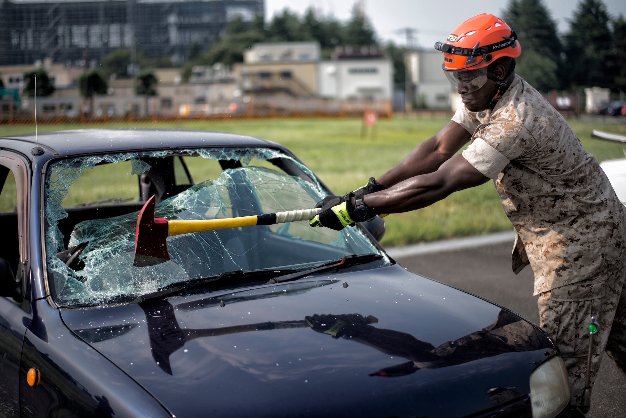 A Marine Corps Air Station Iwakuni firefighter chips away at the windshield during a vehicle extrication demonstration Aug. 4, 2015, at Yokota Air Base, Japan. The windshield is removed to allow firefighters to gain access to a crash victim.  (U.S. Air Force photo by Airman 1st Class Delano Scott/Released)