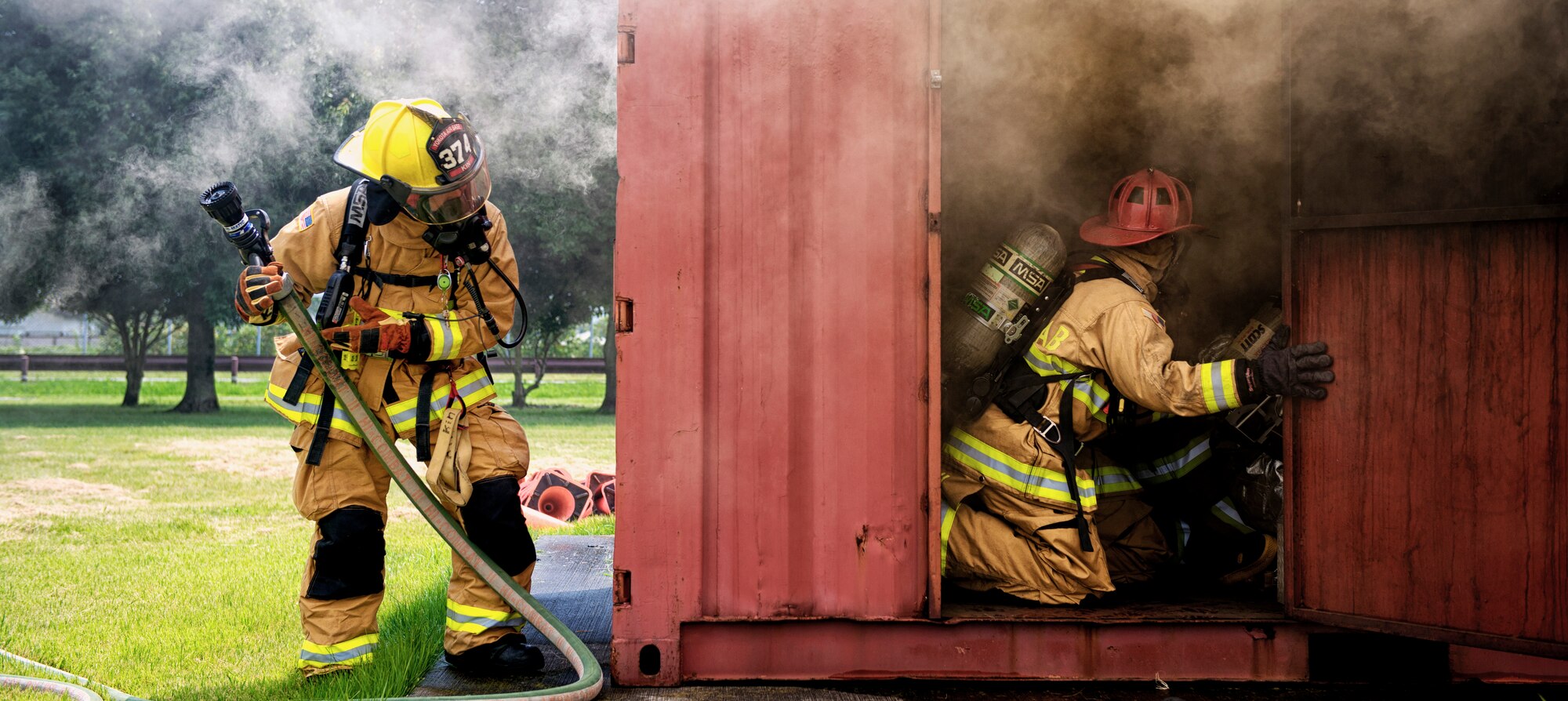 Yokota Air Base and Marine Corps Air Station Iwakuni firefighters battle a simulated fire in a flashover trainer at Aug. 4, 2015, at Yokota Air Base, Japan. Flashover, a near-simultaneous ignition of many objects in a confined room, creates a dangerous situation where both heat and smoke continue to increase until combustion. The joint training exercise taught firefighters how to recognize when a flashover is going to occur and how to suppress it long enough to escape. (U.S. Air Force photo by Airman 1st Class Delano Scott/Released)