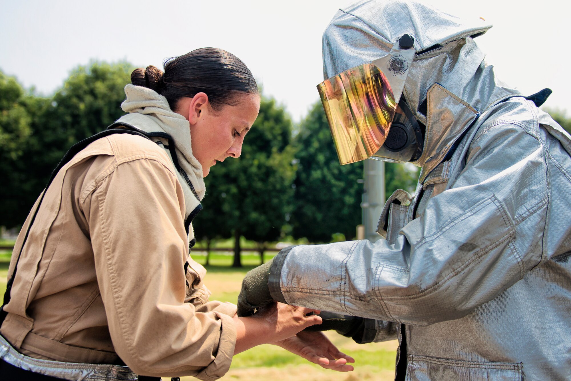Firefighters from Marine Corps Air Station Iwakuni help each other don their protective equipment before entering a flashover trainer Aug. 4, 2015, at Yokota Air Base, Japan. Flashover, a near-simultaneous ignition of many objects in a confined room, creates a dangerous situation where both heat and smoke continue to increase until combustion. Yokota firefighters participated in this annual joint, bilateral training exercise with the Marine firefighters to learn and recognize the signs of a flashover. (U.S. Air Force photo by Airman 1st Class Delano Scott/Released)