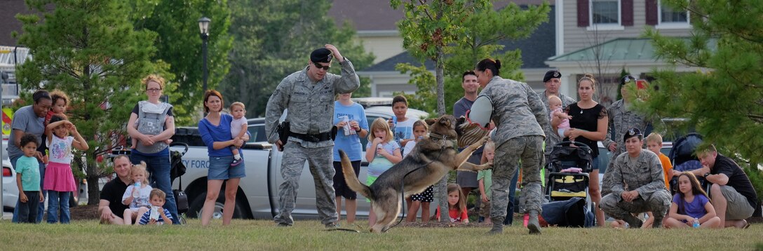 Joint Base Andrews families watch a military working dog display during the National Night Out August 4, 2015, at the Liberty Park Housing Center on JBA, Md. National Night Out showcases the importance of police-community partnerships and citizen involvement in building a safer community.(U.S. Air Force photo by Senior Airman Preston Webb/Released)