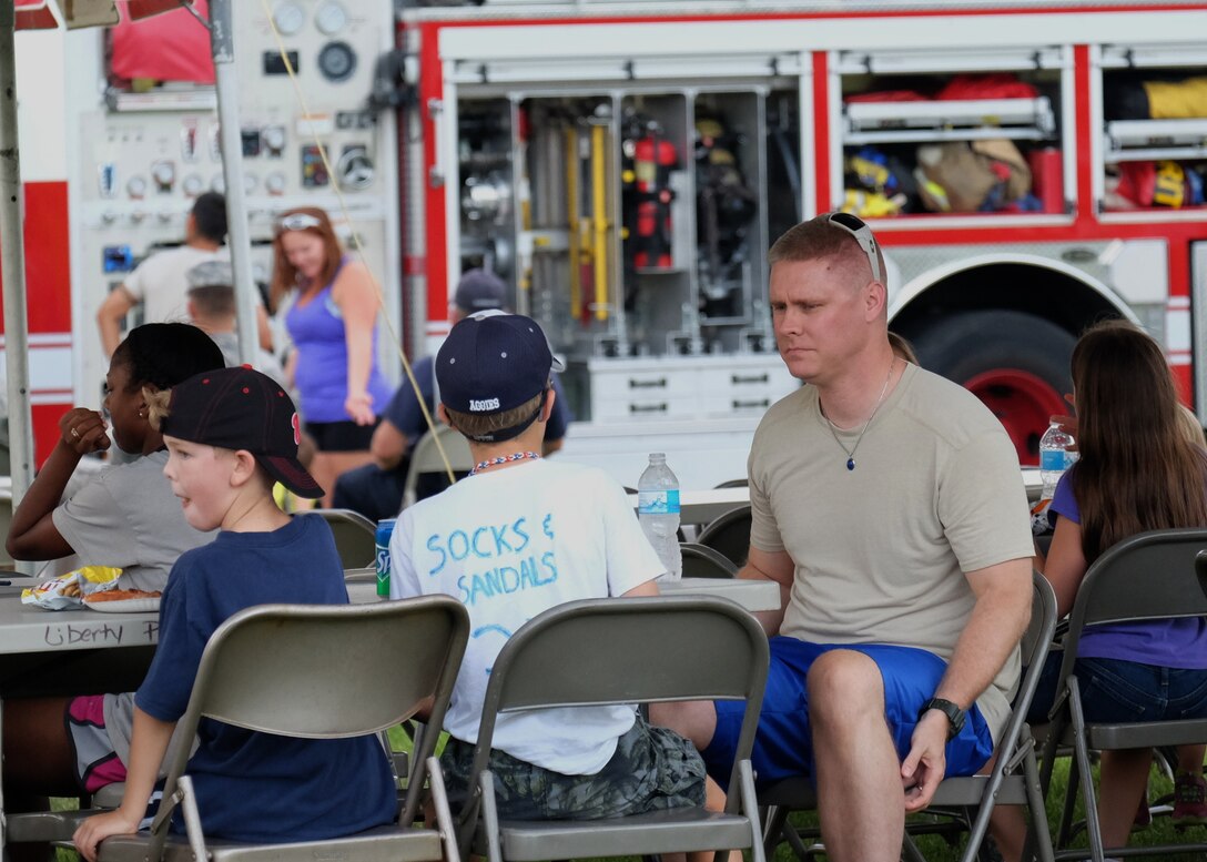 Joint Base Andrews families share snacks and view static displays during the National Night Out August 4, 2015, at the Liberty Park Housing Center on JBA, Md. Displays and showcases included kids vs. cops basketball game, coloring and fingerprinting, a military working dog demonstration, a fire truck display, and a patrol car display. (U.S. Air Force photo by Senior Airman Preston Webb/Released)