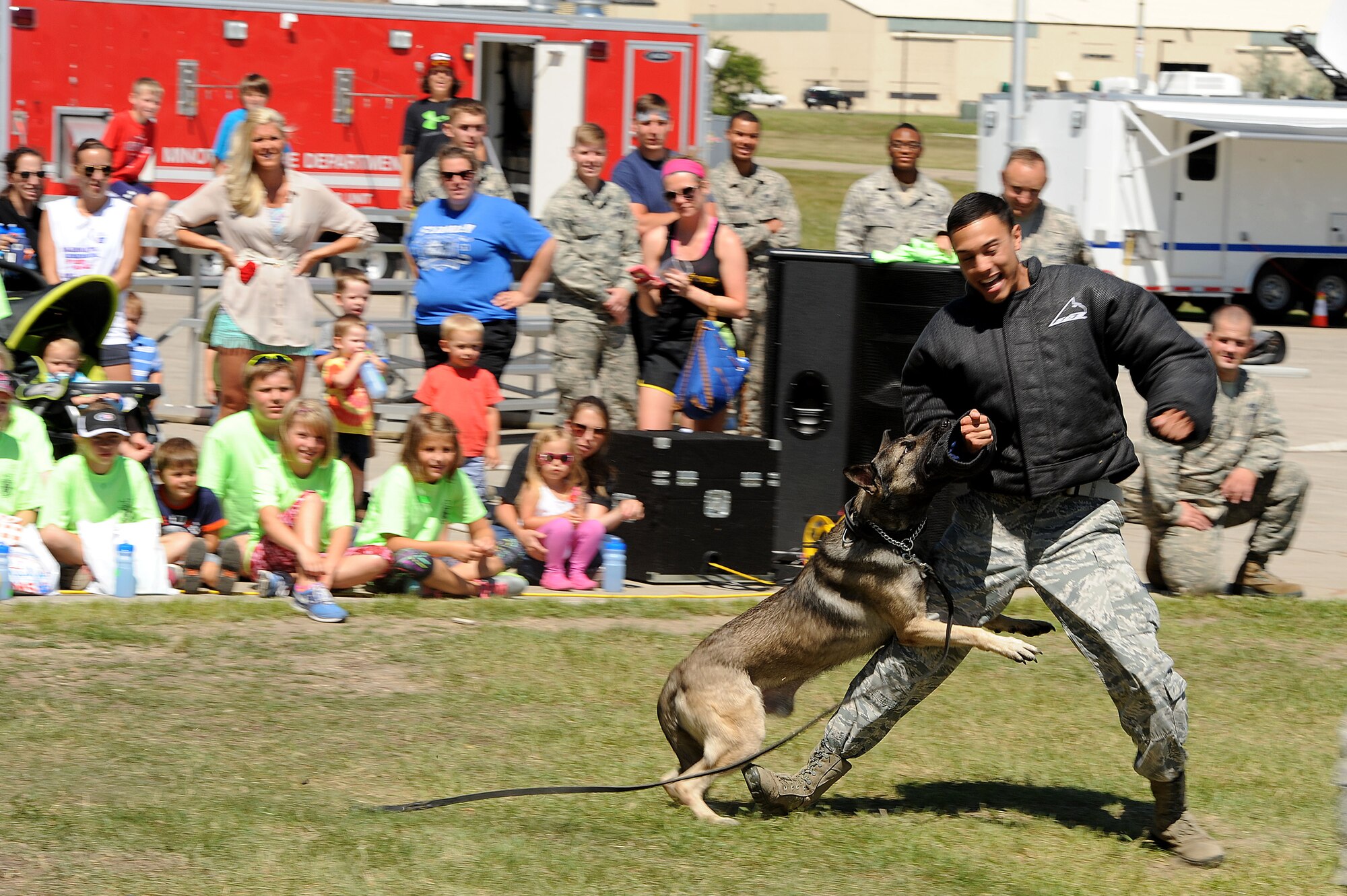 Staff Sgt. Matthew Baxter, 5th Security Forces Squadron K-9 handler, tries to escape military working dog Topi during the “Hero in Training” event at Minot Air Force Base, N.D., July 31, 2015. The event showcased displays from the fire department, security forces squadron, medical group and other base agencies. (U.S. Air Force photo/Senior Airman Kristoffer Kaubisch)