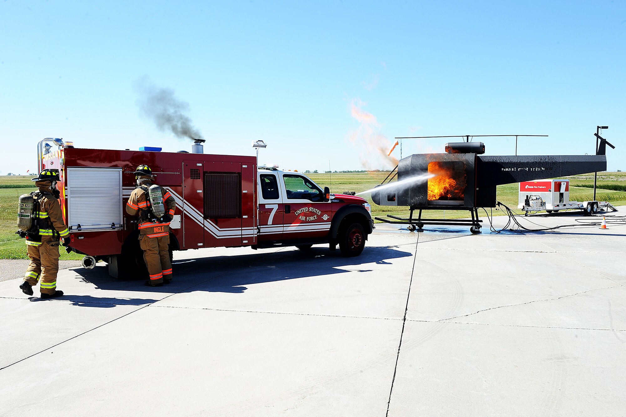 Fire fighters from the 5th Civil Engineer Squadron fire protection flight use their turret from a truck to put out a fire in a training helicopter during the “Hero in Training” event at Minot Air Force Base, N.D., July 31, 2015. The fire department hosted the day-long event which featured displays from their group, the 5th Security Forces Squadron, 5th Medical group and a variety of other base agencies. (U.S. Air Force photo/Senior Airman Kristoffer Kaubisch)