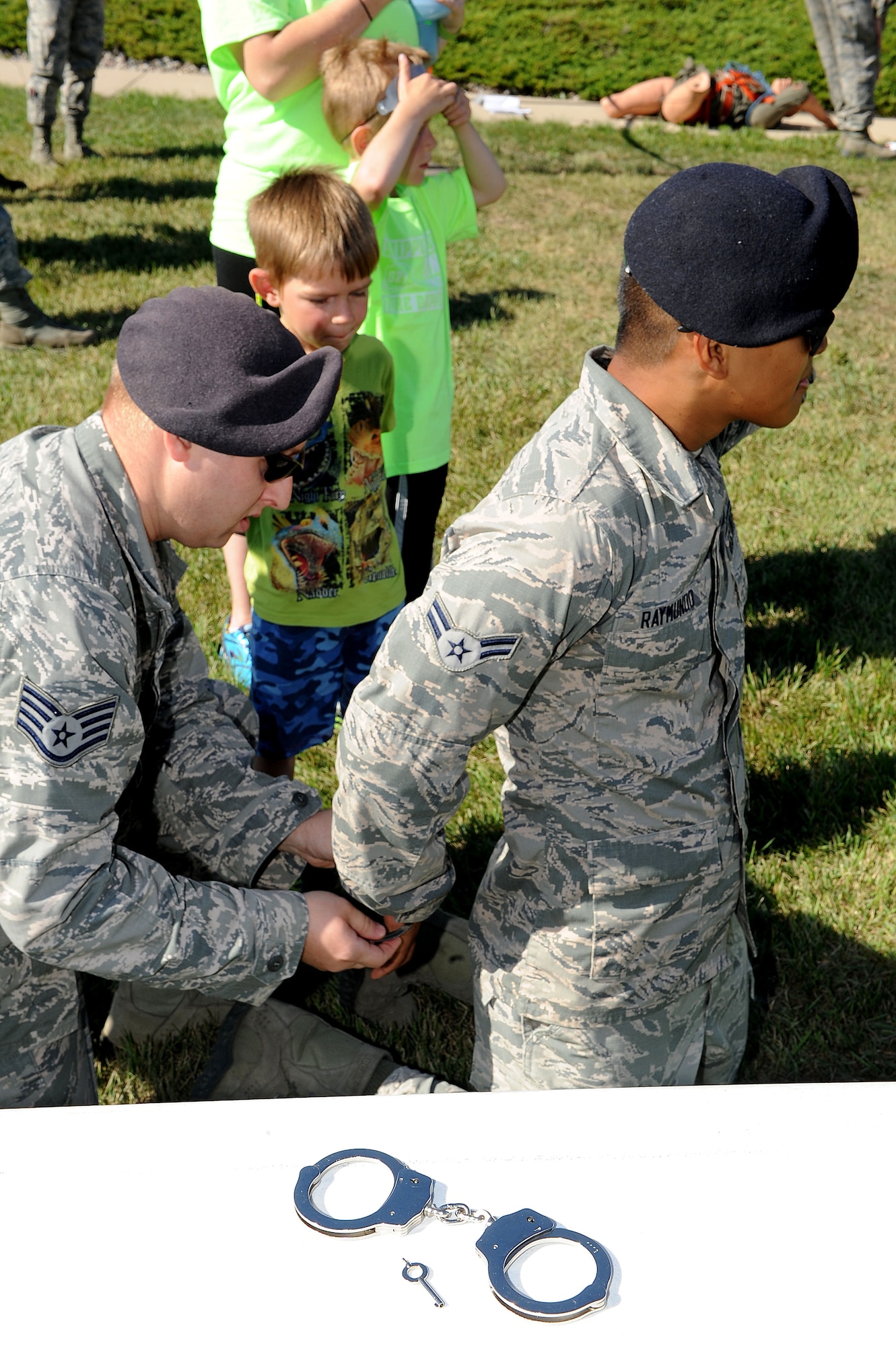 Members of the 5th Security Forces Squadron demonstrate the use of handcuffs during the “Hero in Training” event at Minot Air Force Base, N.D., July 31, 2015. The event showcased displays from the fire department, security forces squadron, medical group and other base agencies. (U.S. Air Force photo/Senior Airman Kristoffer Kaubisch)