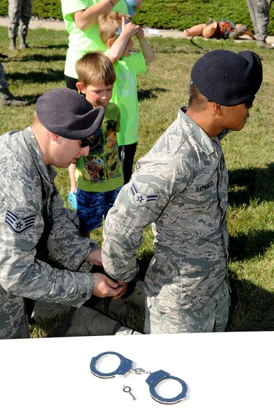 Members of the 5th Security Forces Squadron demonstrate the use of handcuffs during the “Hero in Training” event at Minot Air Force Base, N.D., July 31, 2015. The event showcased displays from the fire department, security forces squadron, medical group and other base agencies. (U.S. Air Force photo/Senior Airman Kristoffer Kaubisch)