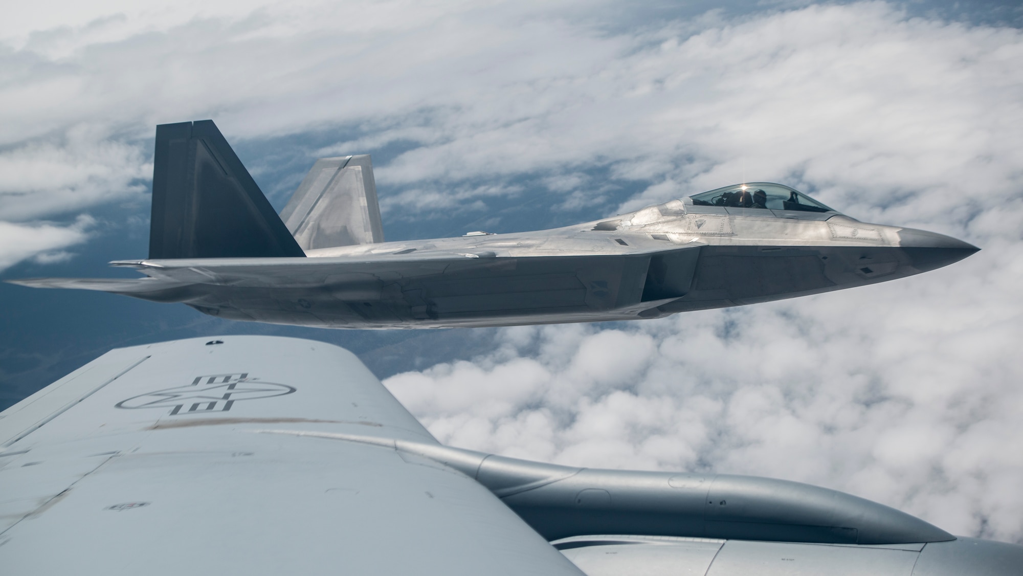 An F-22A Raptor from the 95th Fighter Squadron stationed with the 325th Fighter Wing, Tyndall Air Force Base, Florida, flies beside a KC-135 Stratotanker from the 93rd Air Refueling Squadron Fairchild Air Force Base, Wash., over the Nevada Test and Training Range during Red Flag 15-3 at Nellis AFB, Nevada, July 31, 2015. After receiving fuel the aircrews wait for their wingmen before continuing on with their specific mission. The exercise is conducted above the 2.9 million square acre NTTR north of Las Vegas. (U.S. Air Force photo by Senior Airman Brittany A. Chase)