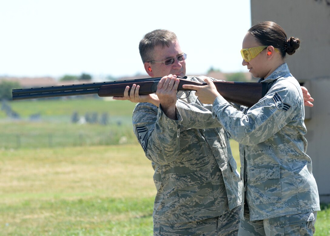Chief Master Sgt. Kevin Peterson, 28th Bomb Wing command chief, assists Senior Airman Karina Quinones-Roberts, 28th Civil Engineer Squadron engineering support technician, during a trap and skeet event at Ellsworth Air Force Base, S.D., July 23, 2015. Peterson hosted the event for Airmen as a way to introduce them to outdoor activities the base has to offer, as well as providing an opportunity to meet others with similar interests. (U.S. Air Force photo by Senior Airman Rebecca Imwalle/Released)