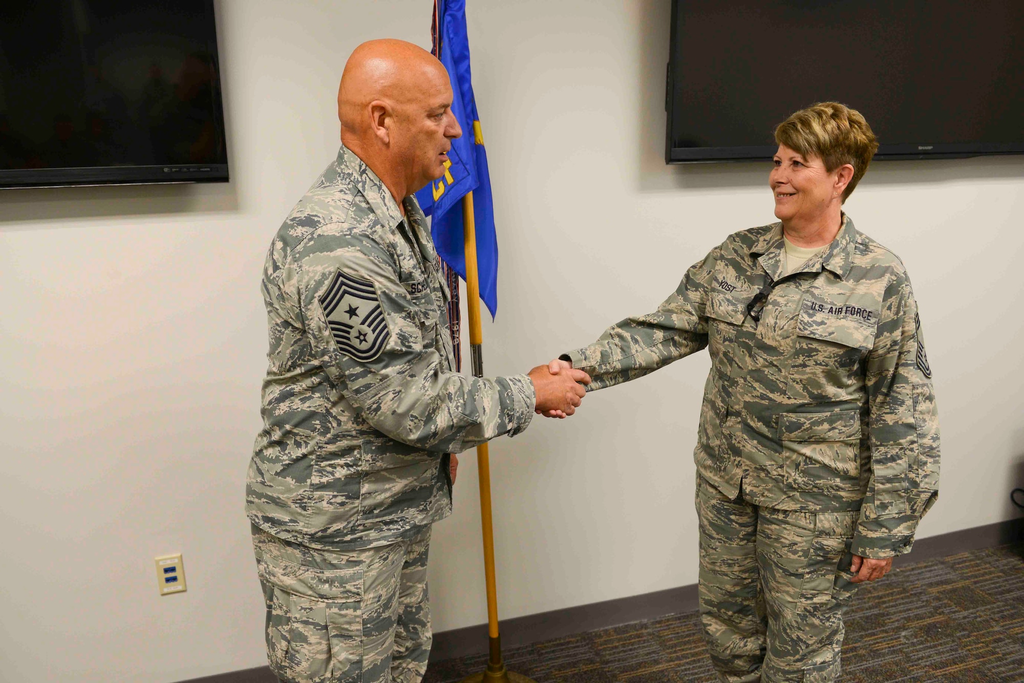 Command Chief Master Sergeant Ed Schellhase (left) presents his coin to theChief of Communications Flight, Chief Master Sergeant Michelle Yost (right) during roll call at the 132d Wing, Des Moines Iowa on Sunday, August 2, 2015.   (U.S. Air National Guard photo by Senior Airman Michael J. Kelly/Released)