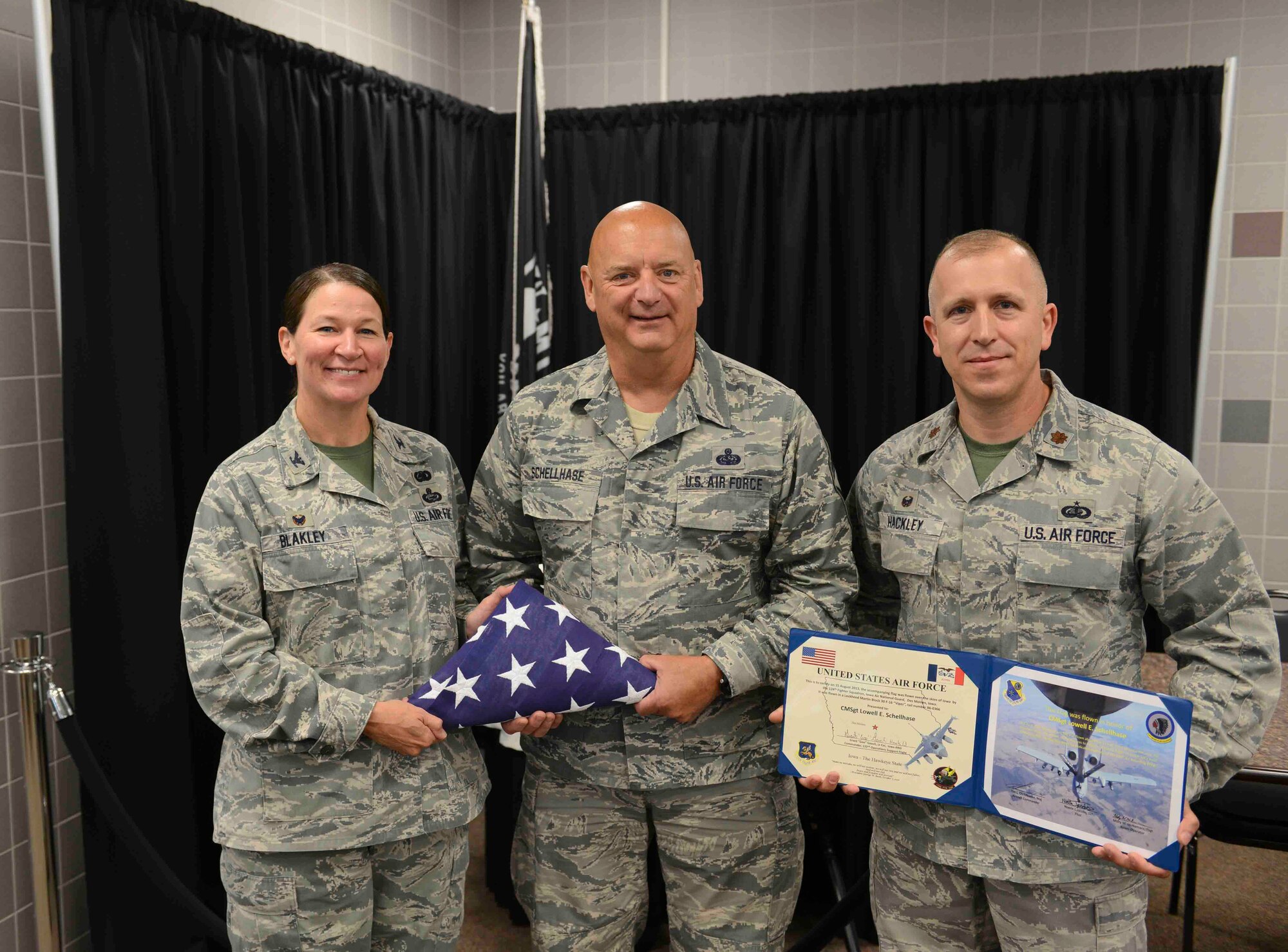 Command Chief Master Sergeant Ed Schellhase (center) receives an honorary flag from Colonel Monica Blakely (left) and Major Glen Hackley (right) at the 132d Wing in Des Moines, Iowa on Sunday August 2, 2015.  (U.S. Air National Guard photo by Senior Airman Michael J. Kelly/Released)