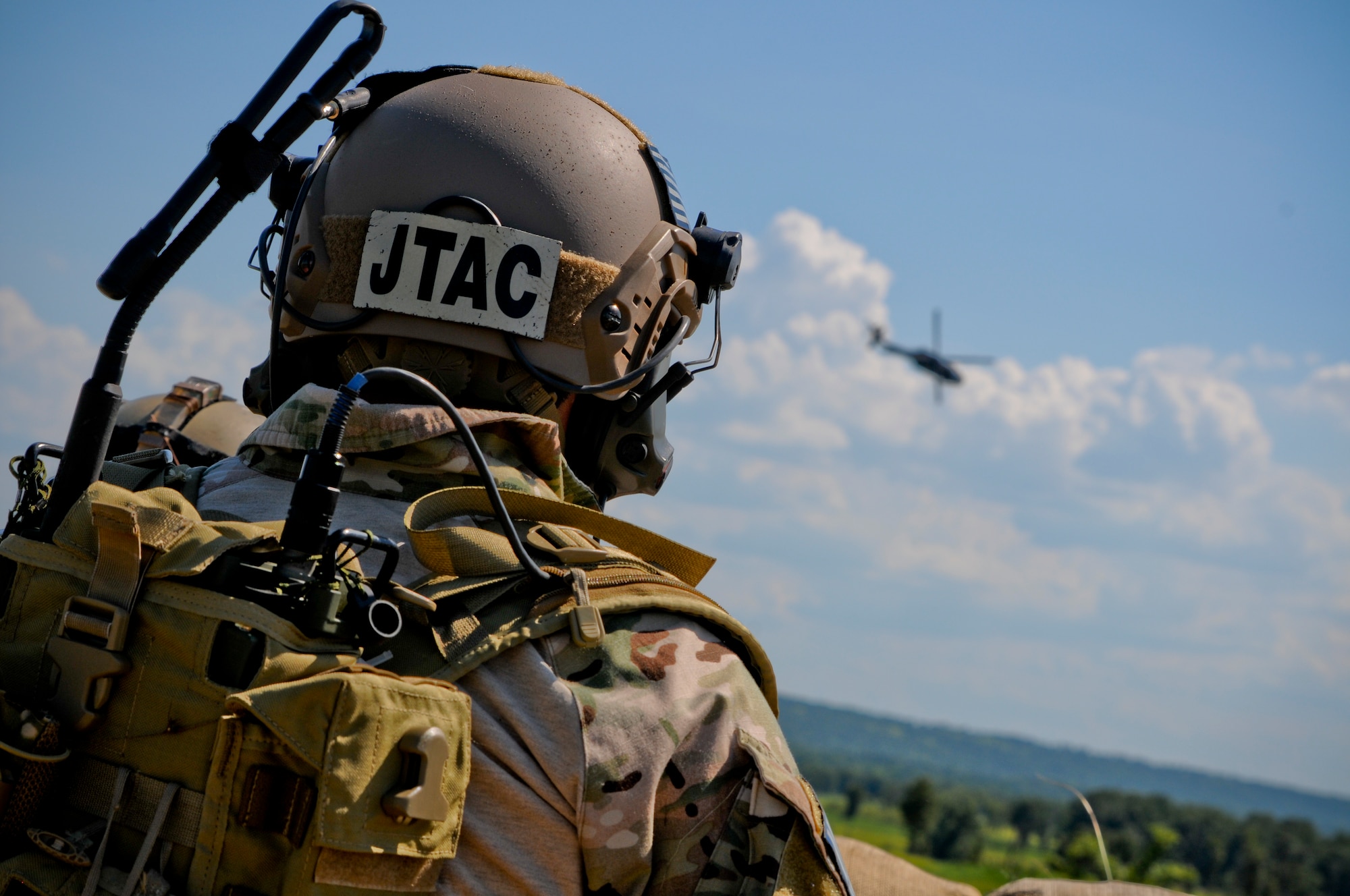 Tech. Sgt. Robert Ellis, Detachment 1 Joint Terminal Attack Controller liaison and evaluator, looks into the distance as an Army UH-60 Black Hawk helicopter performs a show of force flyover during a training simulation at Razorback Range Det. 1 Aug. 1, 2015. Ellis, along with his joint training partners in the Army and Navy, participated in a simulated training event demonstrating the unique capabilities of Razorback Range Det. 1 located at Fort Chaffee Maneuver Training Center, Ark. (U.S. Air National Guard photo by Capt. Holli Nelson/Released)