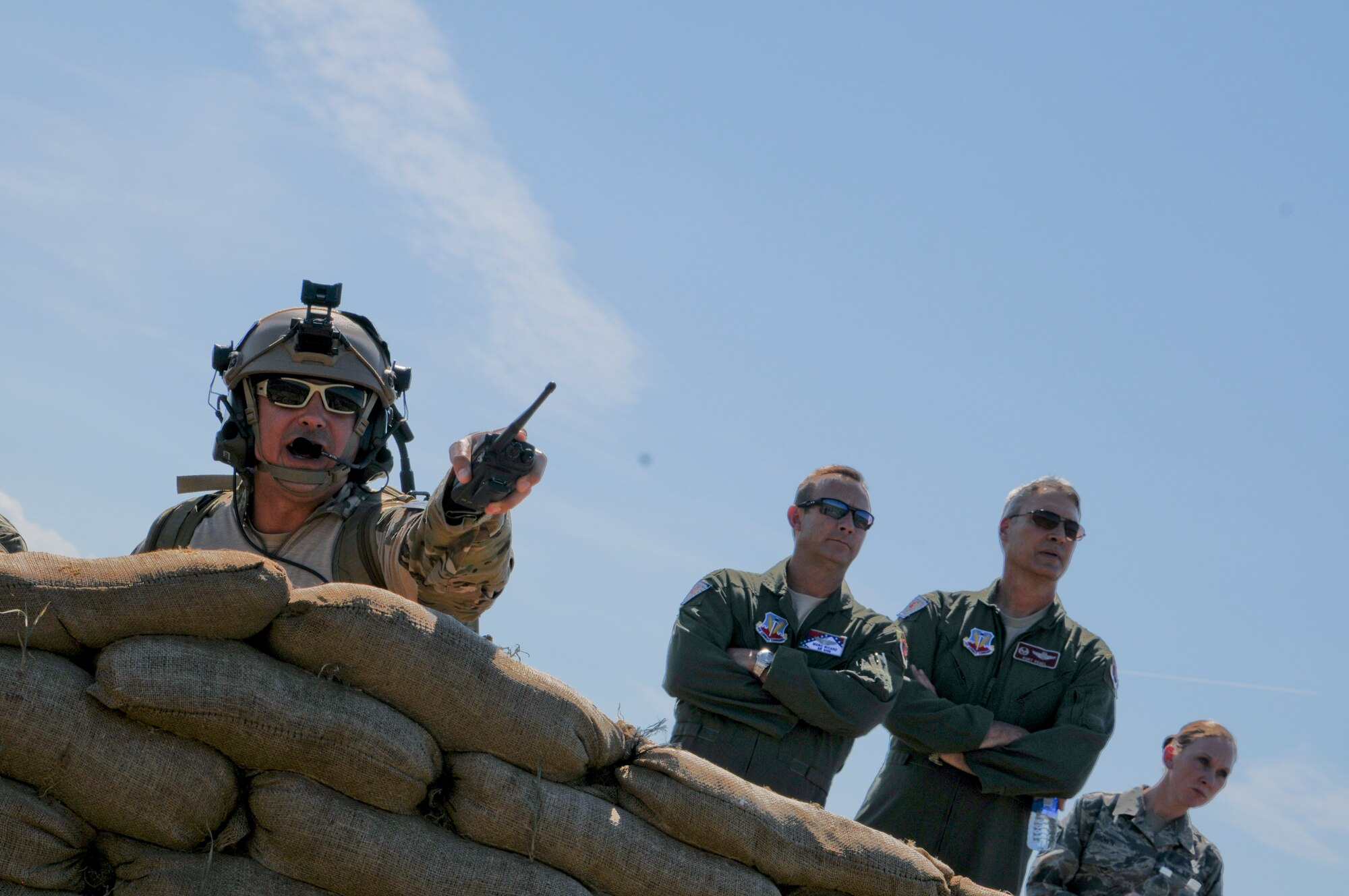 Tech. Sgt. Robert Ellis, Detachment 1 Joint Terminal Attack Controller liaison and evaluator, points to a simulated target as Brig. Gen. Kurt Vogel, commander of the Arkansas Air National Guard, and Col. Marc Sicard, director of staff for the Arkansas Air National Guard, watch in the distance Aug. 1, 2015. Ellis, along with his joint training partners in the Army and Navy, participated in a simulated training event demonstrating the unique capabilities of Razorback Range Det. 1 located at Fort Chaffee Maneuver Training Center, Ark. (U.S. Air National Guard photo by Capt. Holli Nelson/Released)