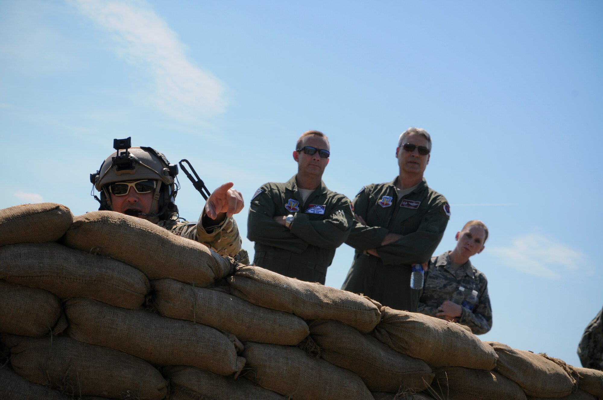 Tech. Sgt. Robert Ellis, Detachment 1 Joint Terminal Attack Controller liaison and evaluator, points to a simulated target as Brig. Gen. Kurt Vogel, commander of the Arkansas Air National Guard, and Col. Marc Sicard, director of staff for the Arkansas Air National Guard, watch in the distance Aug. 1, 2015. Ellis, along with his joint training partners in the Army and Navy, participated in a simulated training event demonstrating the unique capabilities of Razorback Range Det. 1 located at Fort Chaffee Maneuver Training Center, Ark.. (U.S. Air National Guard photo by Capt. Holli Nelson/Released)