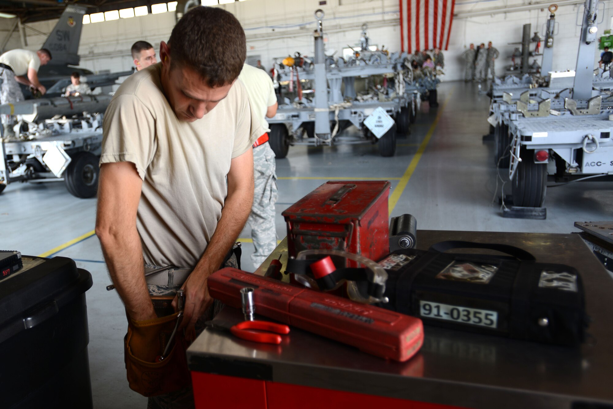 U.S. Air Force Airman 1st Class Jacob Wilson, 20th Aircraft Maintenance Squadron, 77th Aircraft Maintenance Unit weapons load crew member, reaches into his bag in search of tools during a weapons load crew of the quarter competition at Shaw Air Force Base, S.C., July 31, 2015. The competition is held once per quarter to determine which load crew from the three AMUs here can perform the task safely and accurately in the shortest amount of time. (U.S. Air Force photo by Airman 1st Class Kelsey Tucker/Released)