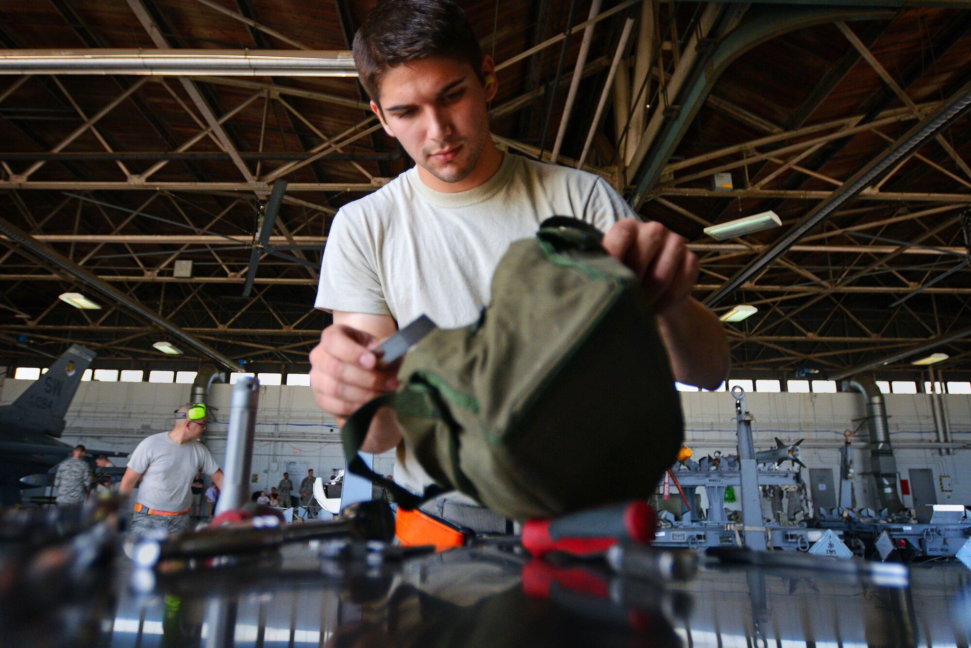 U.S. Air Force Senior Airman Christopher Crawford, 20th Aircraft Maintenance Squadron, 79th Aircraft Maintenance Unit weapons load crew member, checks his tool bag during a weapons load crew of the quarter competition at Shaw Air Force Base, S.C., July 31, 2015.  Crews compete on a quarterly basis to determine who can accurately load F-16CM Fighting Falcon munitions while racing against the clock. (U.S. Air Force photo by Senior Airman Jensen Stidham/Released)