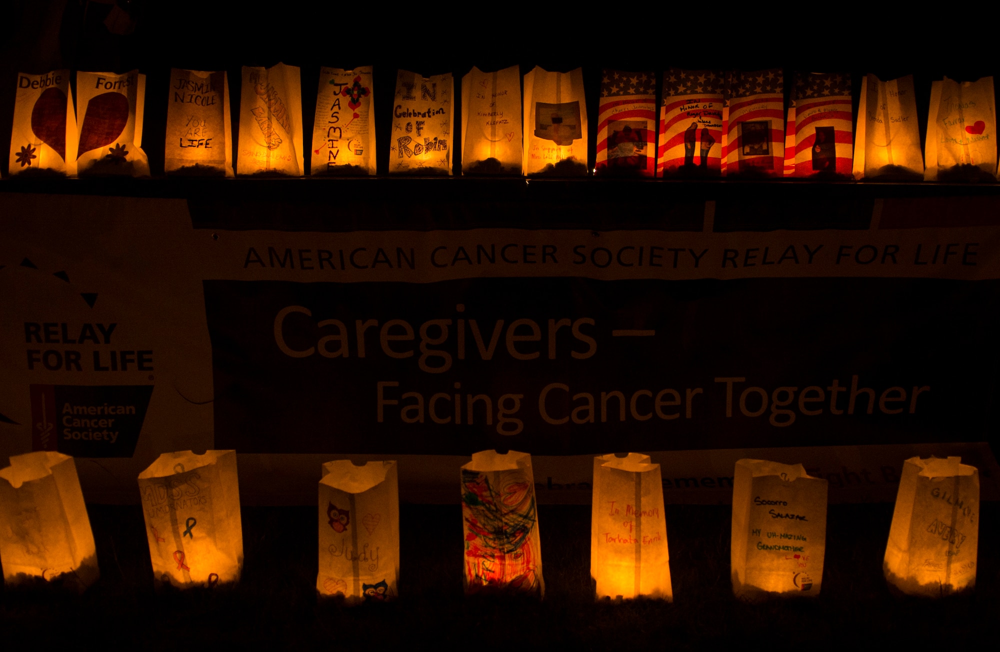 Luminaria bags illuminate a Relay for Life sign during the Relay for Life event at the outdoor track on Spangdahlem Air Base, Germany, July 31, 2015. Participants decorated luminaria bags in dedication to those lost to cancer, those still battling the disease and those who survived their diagnosis. (U.S. Air Force photo by Airman 1st Class Luke Kitterman/Released)
