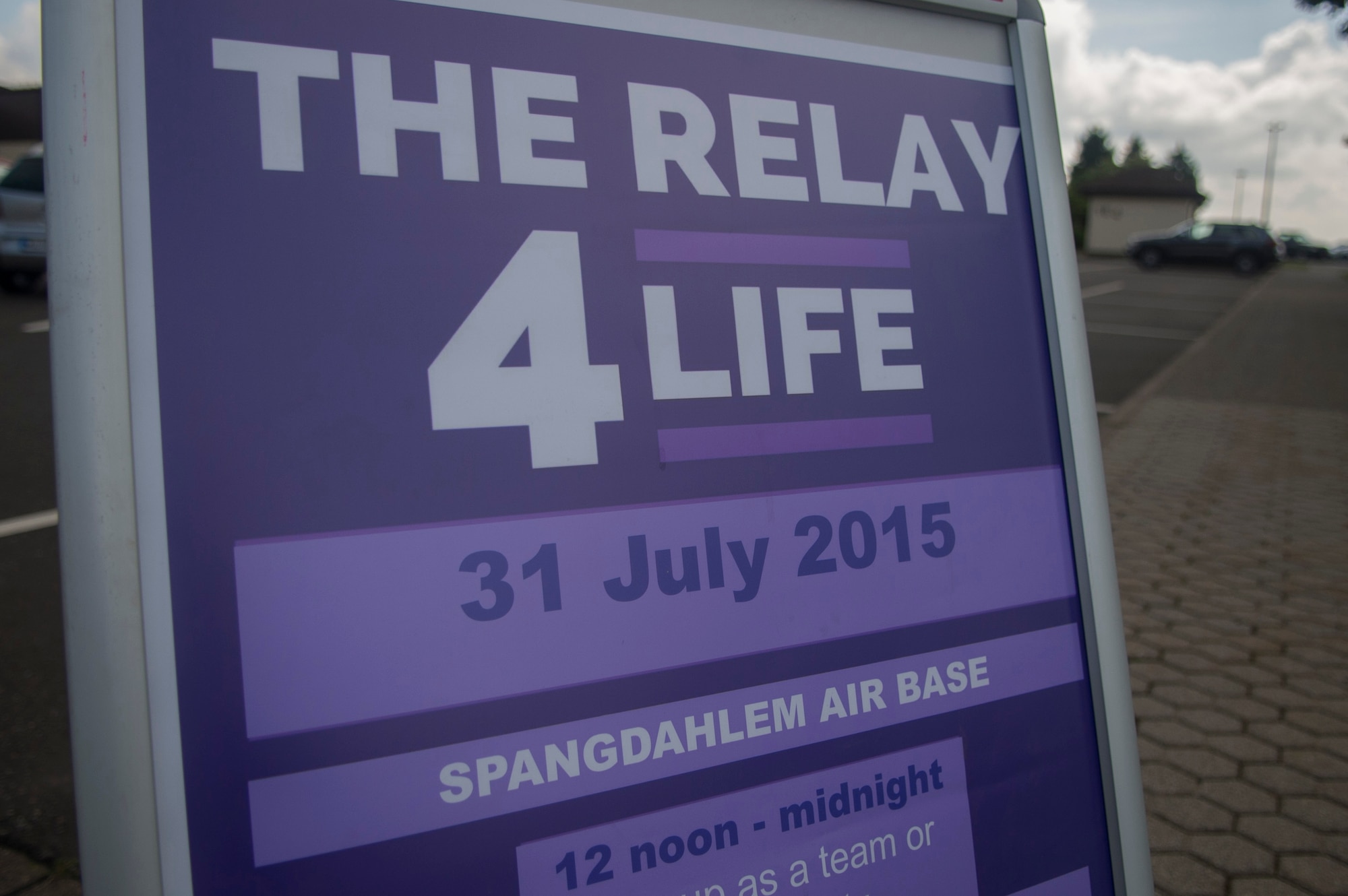A sign displays the Relay for Life event information next to the outdoor track at Spangdahlem Air Base, Germany, July 31, 2015. The event raised more than $23,000 in support funding cancer research development and improving quality of life for patients by providing lodging facilities, transportation and support programs. (U.S. Air Force photo by Airman 1st Class Luke Kitterman/Released) 