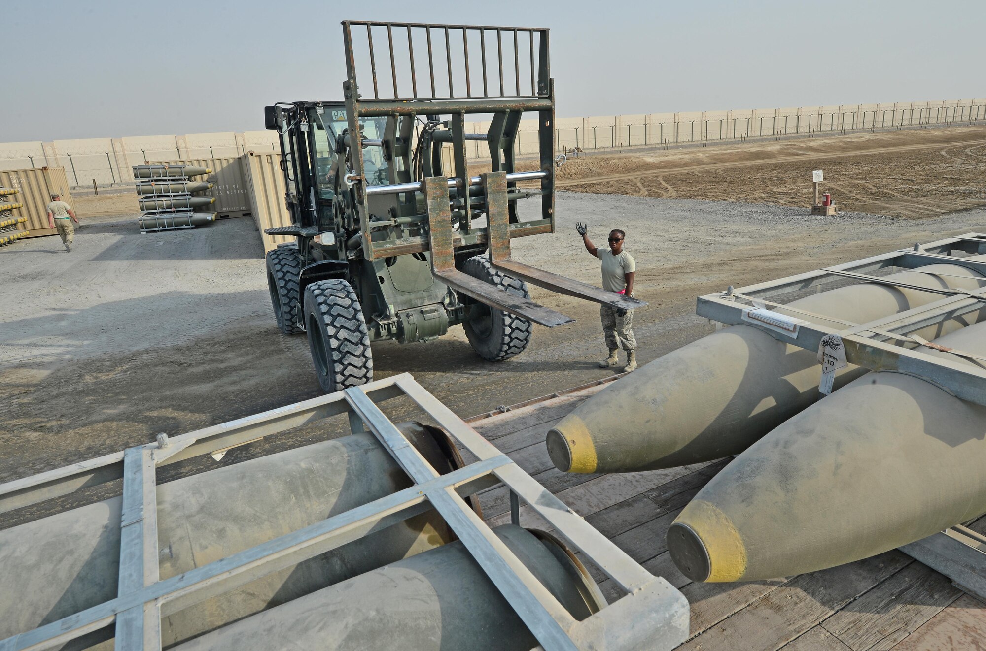Staff Sgt. Charlai, Expeditionary Maintenance Squadron munitions storage crewchief, spots a forklift at an undisclosed location in Southwest Asia July 30, 2015. Upon arrival, munitions are stockpiled in designated areas until they are ready to be transported for final assembly. (U.S. Air Force/Tech. Sgt. Jeff Andrejcik)