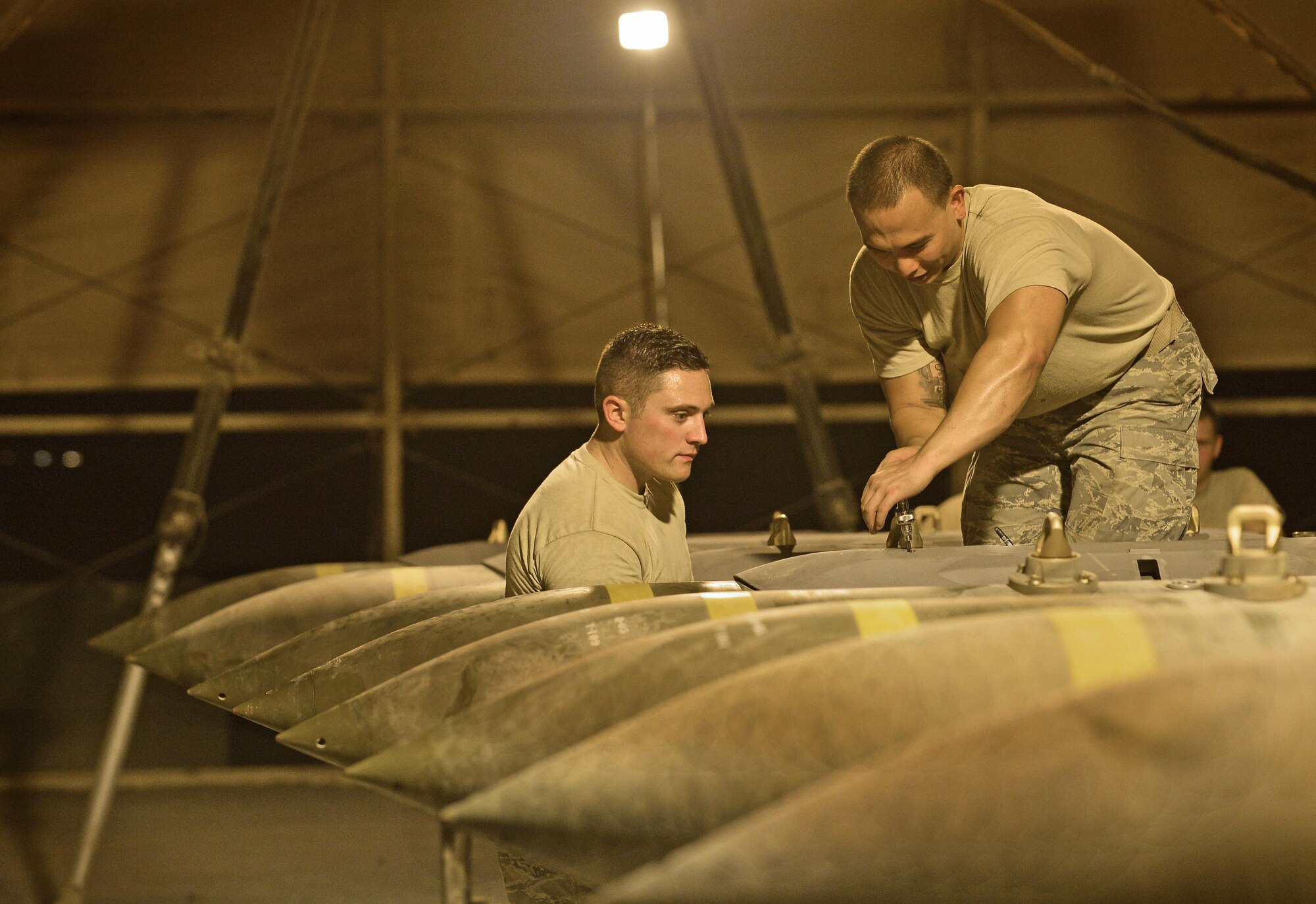 Senior Airman Robert, left, and Steven, Expeditionary Maintenance Squadron conventional maintenance crewmembers, secure the bolts on a Guided Bomb Unit 31 version 3 hardback assembly at an undisclosed location in Southwest Asia July 30, 2015. Once the bombs are finished being built they are held in a designated area until an Air Tasking Order is received. The GBU-31 is a hardened target penetrator bomb manufactured here to meet the objectives of OPERATION INHERENT RESOLVE and FREEDOM SENTINEL, multi-national efforts to eliminate the Islamic State in Iraq and the Levant, or ISIL.  (U.S. Air Force photo/Tech. Sgt. Jeff Andrejcik)