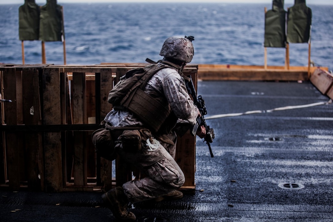 INDIAN OCEAN (July 30, 2015) A U.S. Marine with Lima Company, Battalion Landing Team 3rd Battalion, 1st Marine Regiment, 15th Marine Expeditionary Unit, drops to a knee to engage his target during a deck shoot aboard the amphibious assault ship USS Essex (LHD 2). The Marines practiced shooting from behind a barricade to simulate staying behind cover during a fire fight. The 15th MEU is embarked on the Essex Amphibious Ready Group and deployed to maintain regional security in the U.S. 5th Fleet area of operations. (U.S. Marine Corps photo by Cpl. Elize McKelvey /Released)