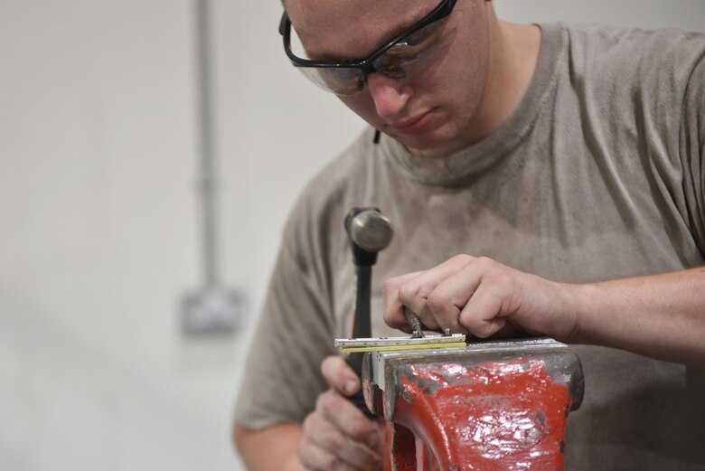 Senior Airman Adam Bentz, 379th Expeditionary Maintenance Squadron's fabrication flight, adjusts a KC-135 Stratotanker spoiler access panel part before returning to the flight line for application August 4, 2015 at Al Udeid Air Base, Qatar. The fabrications flight is partitioned into the aircraft structural maintenance and metal technology sections that make on-site repairs to aircraft deployed to Al Udeid. Most fabrications can be conducted on the flight line. For others, Airmen would bring in the part or create what is needed to keep the aircraft flying within hours. (U.S. Air Force photo/ Staff Sgt. Alexandre Montes)