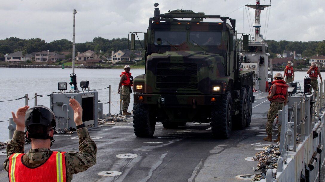 Petty Officer Third Class James Stanley, a beachmaster with Beachmasters Unit Two, directs a Marine with Combat Logistics Regiment 25, driving off the Improved Navy Lighterage System during training at Green Beach Two aboard Marine Corps Support Facility Blount Island and U.S. Coast Guard Sector Jacksonville, North Carolina Aug. 4, 2015. The Marines with CLR-25 practiced driving various vehicles on and off the INLS to prepare for loading and unloading material from the craft later on in the week. This exercise, led by the 2nd Marine Expeditionary Brigade and Expeditionary Strike Group Two, is one part of BOLD ALLIGATOR 2014, the year's largest amphibious exercise on the East Coast, which will serve as a capstone event for the Marines' Expeditionary Force 21 concept.