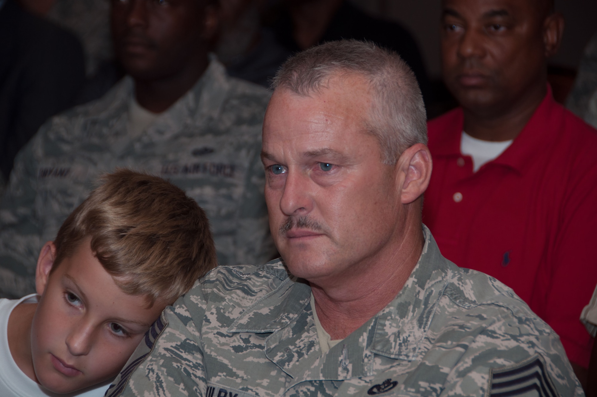 During the inactivation ceremony for the 307th RED HORSE Squadron, U. S. Air Force Chief Master Sgt. Rodney Kilby, a member of the squadron, and his son watch a video of the history of the squadron, Aug. 2, 2015 Barksdale Air Force Base, La. The squadron performed both wartime and humanitarian missions in more than 27 countries during its 44 years of operation. (U.S. Air Force photo by Master Sgt. Laura Siebert)