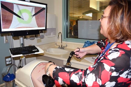 Veterans Affairs Nurse Educator Sui Unzelman uses a simulated laparoscopy machine to practice cutting mesh for surgery during the SIM Center open house July 22.