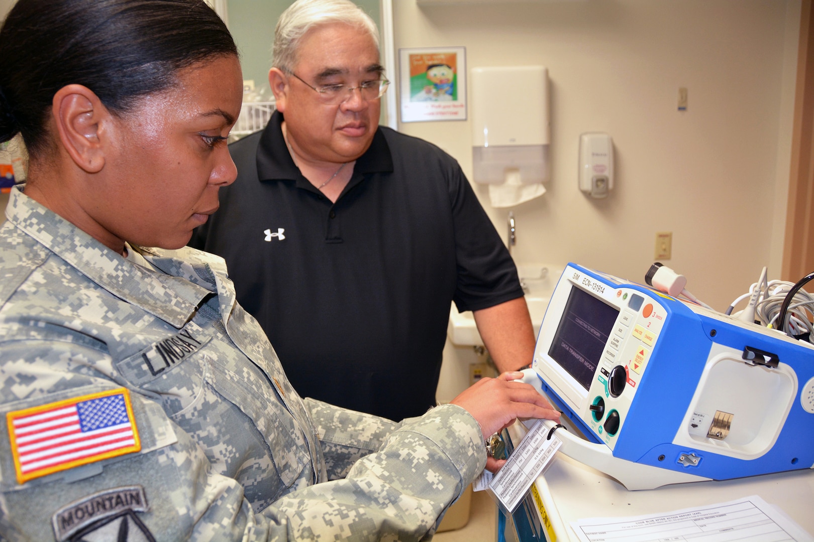 Registered Nurse Maj. Tanesha Lindsay and Simulator Educator Thomas Kai go over defibrillator procedures during the SIM Center open house July 22.