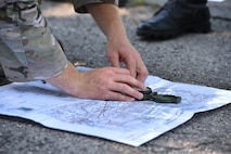 Staff Sgt. Zachariah Angel, Survival, Evasion, Resistance and Escape (SERE) operations craftsman with the 910th Operations Support Squadron, demonstrates how to use a compass and map to determine whereabouts here, July 31, 2015. Angel led approximately ten aircrew members in a combat survival skills training course at Camp Ravenna Joint Military Training Center. The course is a triennial requirement for aircrew members and provides skills for surviving, evading capture, resisting the enemy and escaping a hostile environment. (U.S. Air Force photo/Eric M. White)