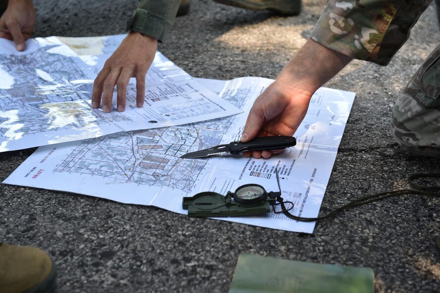 Staff Sgt. Zachariah Angel (right), Survival, Evasion, Resistance and Escape (SERE) operations craftsman with the 910th Operations Support Squadron, points out coordinates on a map of Camp Ravenna here, July 31, 2015. Maj. Vince Repucci (left), a pilot with the 757th Airlift Squadron, studies the map. Approximately ten aircrew members were at Camp Ravenna Joint Military Training Center for an aircrew combat survival skills training course. The course is a triennial requirement for aircrew members and provides skills for surviving, evading capture, resisting the enemy and escaping a hostile environment. (U.S. Air Force photo/Eric M. White)  