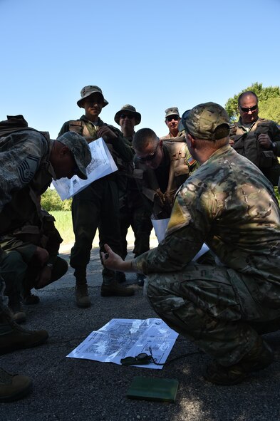 Staff Sgt. Zachariah Angel, Survival, Evasion, Resistance and Escape (SERE) operations craftsman with the 910th Operations Support Squadron, demonstrates how to use a compass and map to determine whereabouts here, July 31, 2015. Angel led approximately ten aircrew members in a combat survival skills training course at Camp Ravenna Joint Military Training Center. The course is a triennial requirement for aircrew members and provides skills for surviving, evading capture, resisting the enemy and escaping a hostile environment. (U.S. Air Force photo/Eric M. White)