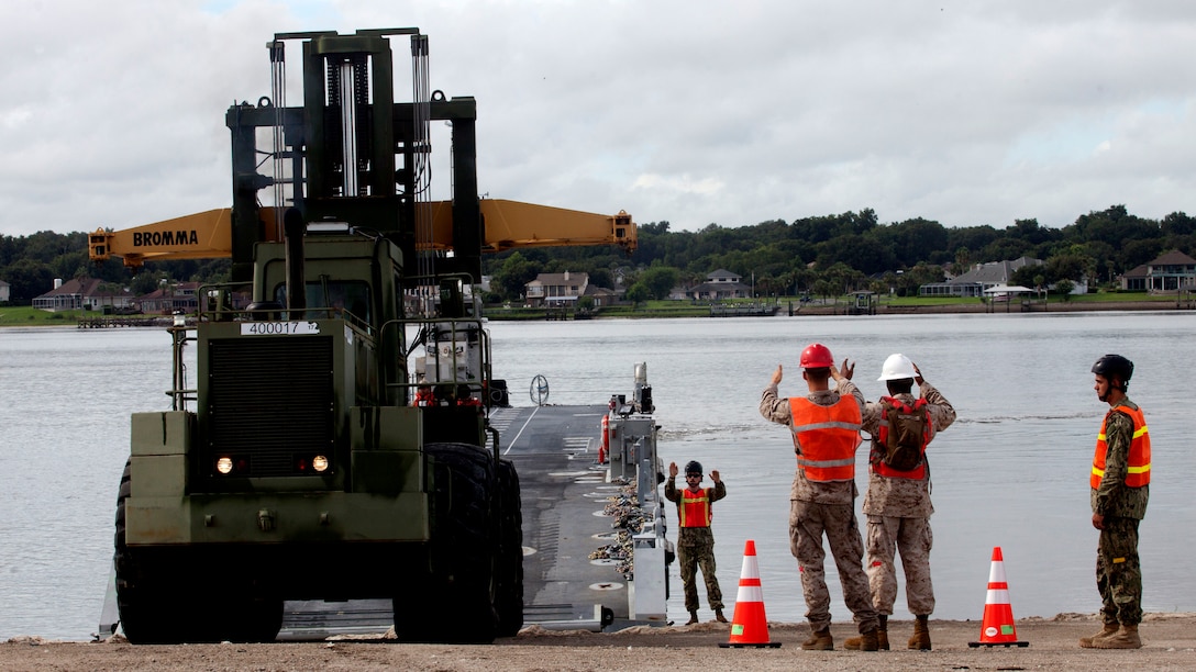 A Marine with Combat Logistics Regiment 25 drives a Rough Terrain Container Handler onto an Improved Navy Lighterage System while being guided by sailors with Amphibious Construction Battalion Two, while training at Green Beach Two aboard Marine Corps Support Facility Blount Island and U.S. Coast Guard Sector Jacksonville, North Carolina Aug. 4, 2015. The Marines with CLR-25 practiced driving various vehicles on and off the INLS to prepare for loading and unloading material from the craft later on in the week. This exercise, led by the 2nd Marine Expeditionary Brigade and Expeditionary Strike Group Two, is one part of BOLD ALLIGATOR 2014, the year's largest amphibious exercise on the East Coast, which will serve as a capstone event for the Marines' Expeditionary Force 21 concept. (Marine Corps photo by Cpl. Austin Long)