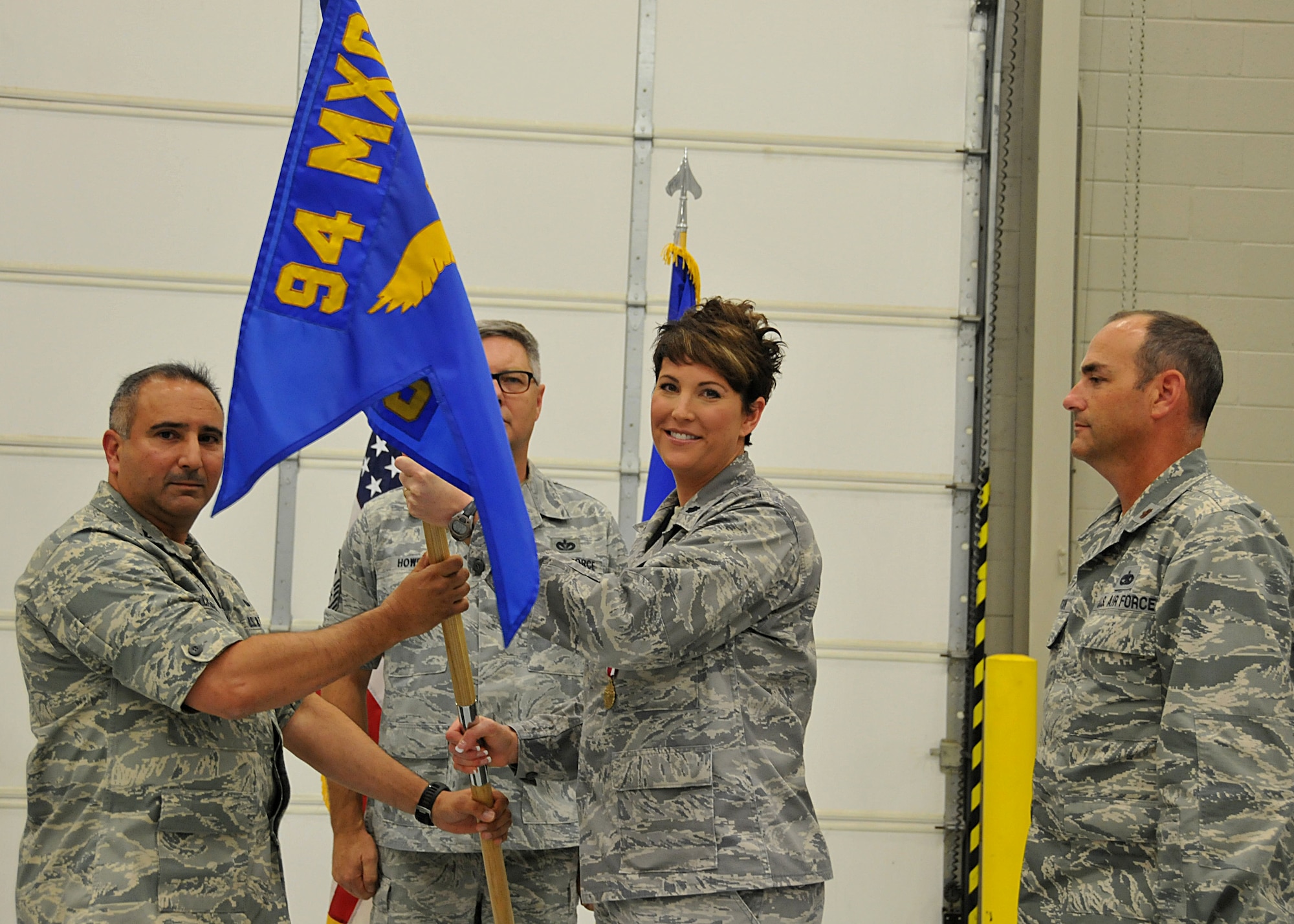 Lt. Col. Kerri Ebrecht hands off the unit flag to Col. Augusto Casado, commander of the 94th Maintenance Group, during the 94th Aircraft Maintenance Squadron change of command ceremony Aug. 2, 2015 at Dobbins Air Reserve Base, Ga. Possession of the flag symbolizes command over the unit.(U.S. Air Force photo/Senior Airman Andrew Park)

