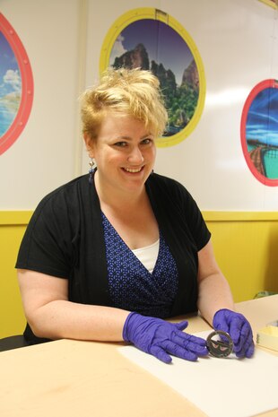 Carrie Bowers, museum specialist in aviation for the National Museum of the Marine Corps, holds a challenge coin from the HMM-163 (Reinforced) Marine Medium Helicopter Squadron, July 20, aboard Marine Corps Base Quantico.
