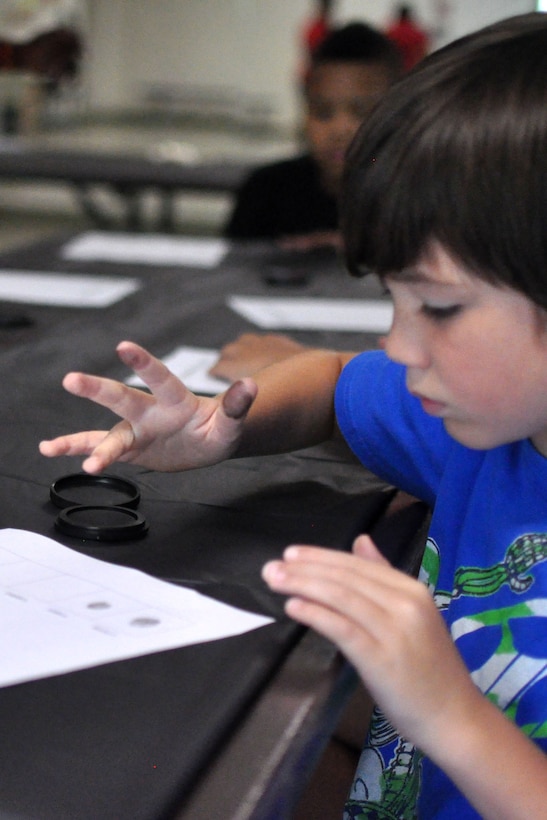 Nathanael, age 9, learns to make fingerprints in a Crime Scene Investigation Workshop July 28 at the Quantico Youth Center. During the week-long camp, children learned how fingerprint analyses are used by investigators to positively identify people for many years.