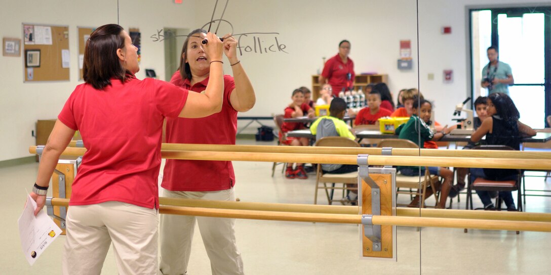 Joey Miranda, director of Quantico Youth Programs, shows a group of children the anatomy of a hair follicle during a Crime Scene Investigation workshop July 28 at The Quantico Youth Center. Miranda teaches the children how to apply scientific methods to criminal investigation. 