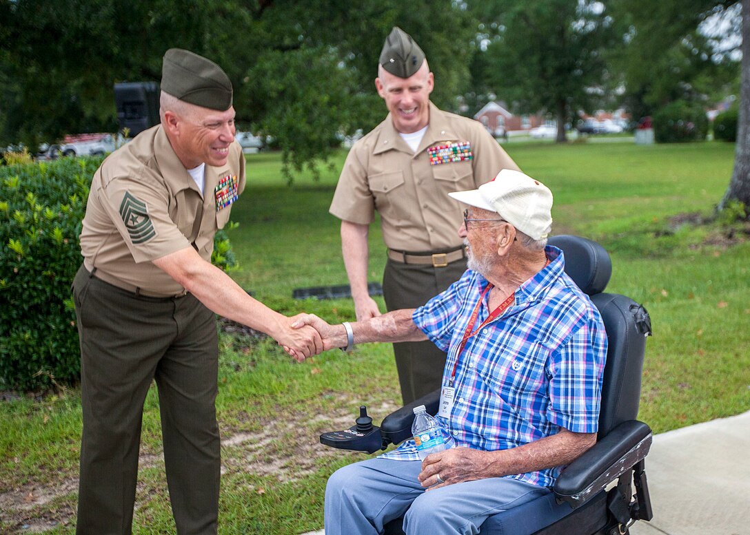 U.S. Marine Corps Sgt. Maj. Paul A. Berry, left, sergeant major of Installations East-Marine Corps Base Camp Lejeune, greets a veteran of the 4th Marine Division before morning colors on Camp Lejeune, N.C., Aug. 4, 2015. Veterans of 4th Marine Division and their families visited the installation for a final muster, which included visits to the Lejeune Memorial Gardens, new equipment demonstrations, tours in the local community, and a deactivation ceremony for the unit.
