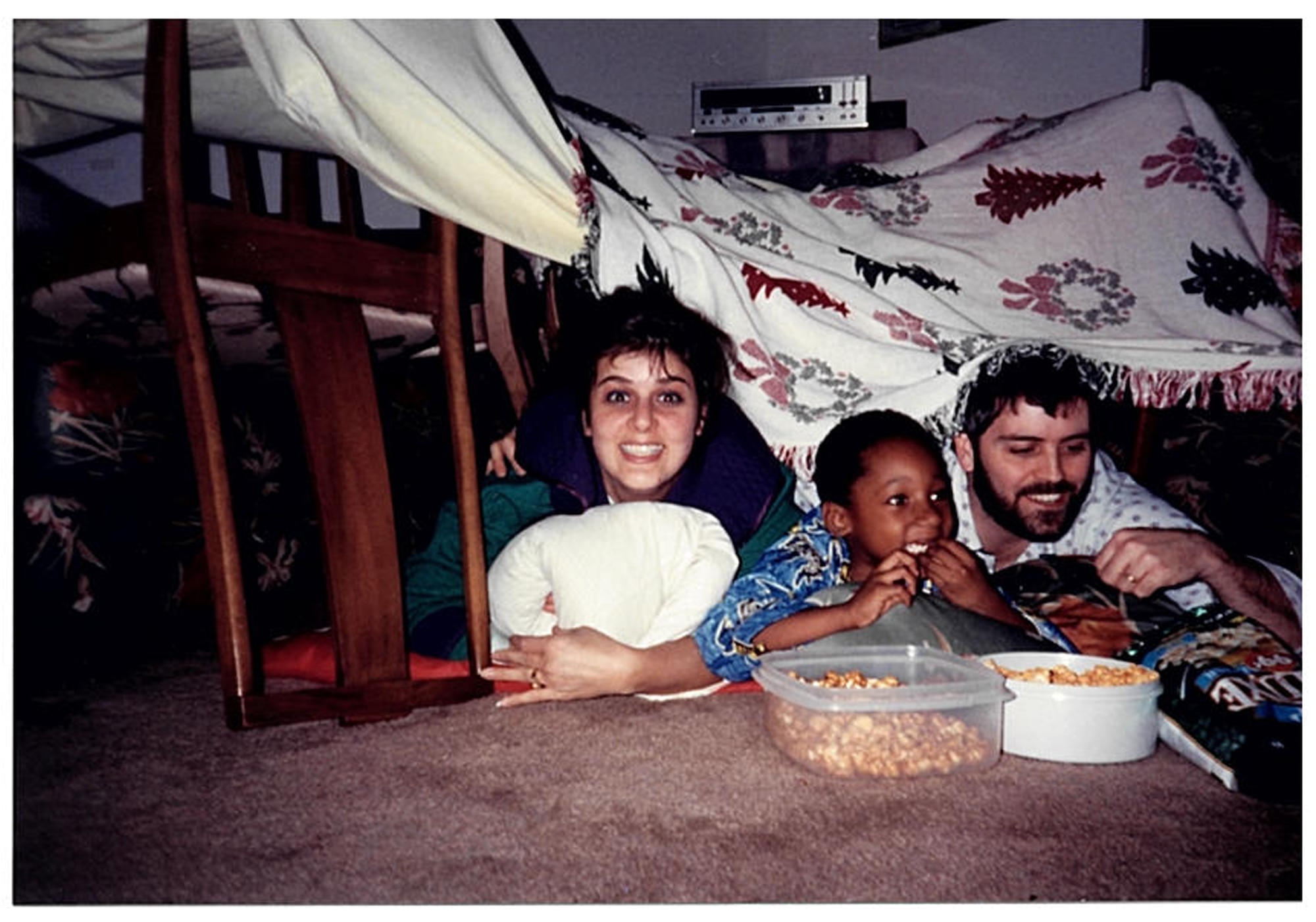Yvonne Meeder, Christopher Bowyer-Meeder and Bruce Meeder, enjoy popcorn under a home-built blanket fort while watching a movie. Bruce and Yvonne became Chris's legal guardians when he was just five-years-old. (U.S. Air Force courtesy photo)