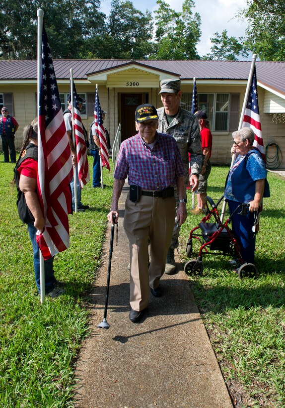 Jules Olivier, Army Air Corps and Air Force veteran, walks down a line of U.S. flags held by Warriors Watch Riders July 31 at his house. Panama City’s Home Depot installed a flag pole for Olivier free of charge, and members of Team Tyndall presented him with an American flag that had been flown over Tyndall. (U.S. Air Force photo by Senior Airman Alex Echols/Released)